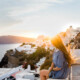 Back view of unrecognizable female traveler admiring Oia Village on Santorini island on windy day in Greece